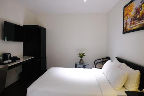 a bedroom with a white bed and a table at Nicecy Boutique Hotel in Ho Chi Minh City