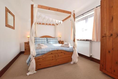 a bedroom with a wooden bed with a canopy at Nuthatch near Huntsham in Tiverton