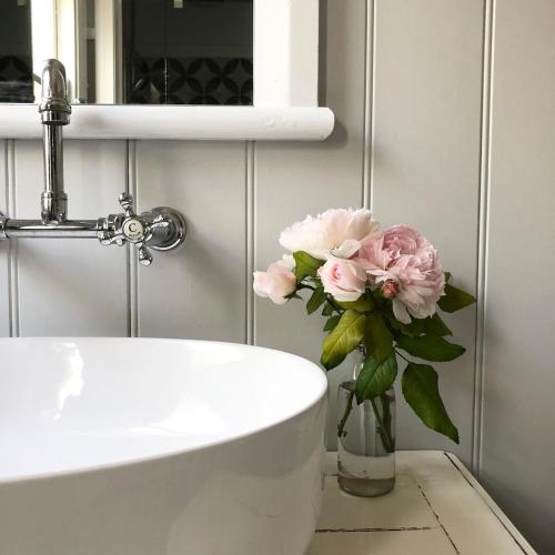 ナウラにあるAudreys Style and comfortのシンクの横に置かれたピンクの花瓶