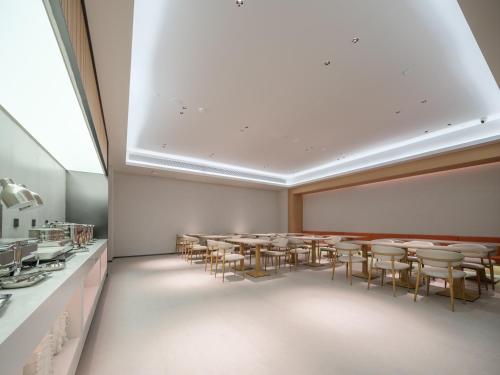 a room with a long table and chairs in it at 桔作酒店 郑州中州大道中原国际博览中心店 in Zhengzhou