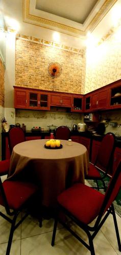 a table in a kitchen with red chairs and a table with fruit on it at Long Homestay Xuyên Á - Hotels in Ðức Hòa