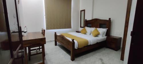a bedroom with a bed with yellow pillows and a desk at Hotel Suryavanshi Palace in Jaipur