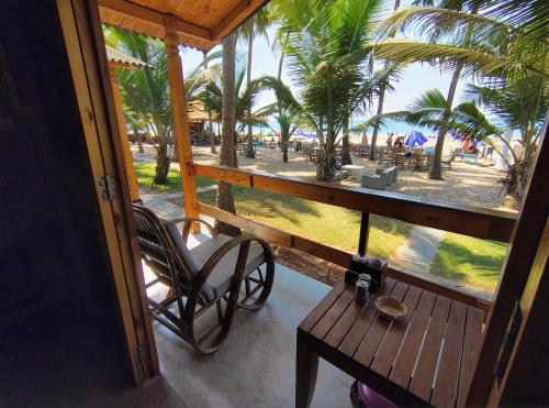 a porch with a bench and a view of the beach at orange sky beach bungalow in Agonda