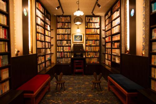 a library with shelves of books and benches at TAKITEI Riverside Onsen ーA Hidden Ryokan in Kanazawaー in Kanazawa