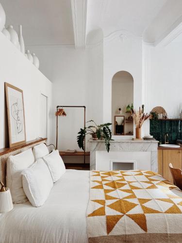 une chambre blanche avec un lit et une cheminée dans l'établissement Maison Acacia - La bibliothèque, à La Ciotat