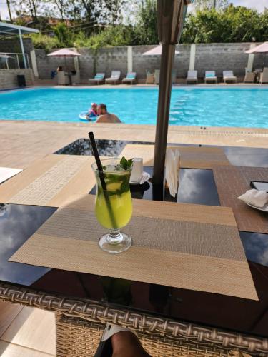 a drink on a table next to a swimming pool at Kivulini Eco Park Karen in Nairobi