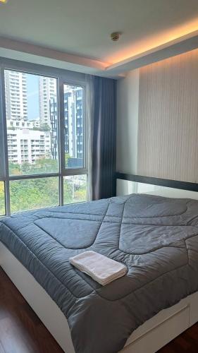 a bedroom with a large bed with a large window at Spacious Sukhumvit Condo near EmQuartier in Bangkok