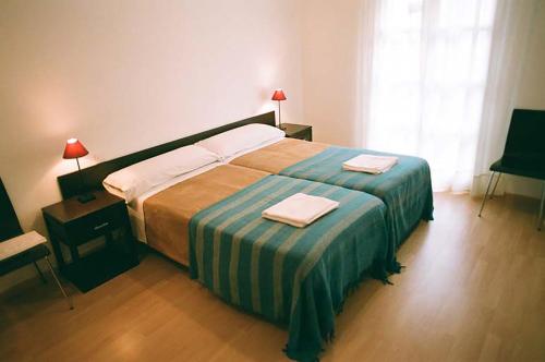 una camera da letto con un letto grande con due asciugamani sopra di Apartamentos Auhabitat Zaragoza, edificio de apartamentos turísticos a Saragozza