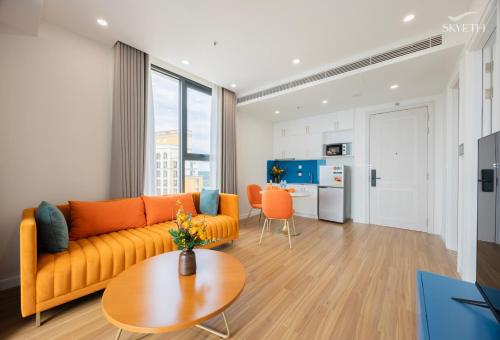 a living room with an orange couch and a table at Luna Sol Villas - Dedicated Care Until Check Out in Phu Quoc