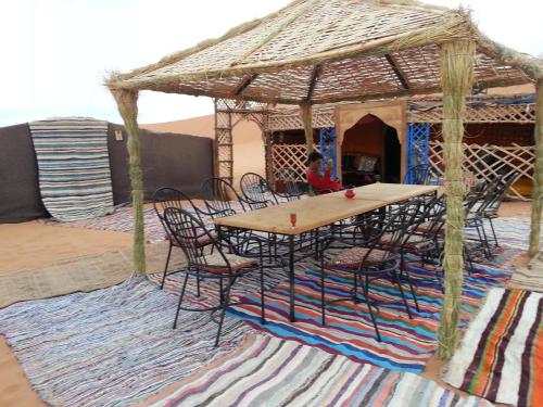 une table avec des chaises et un kiosque sur un tapis dans l'établissement Bivouac Le Petit Prince Merzouga, à Merzouga