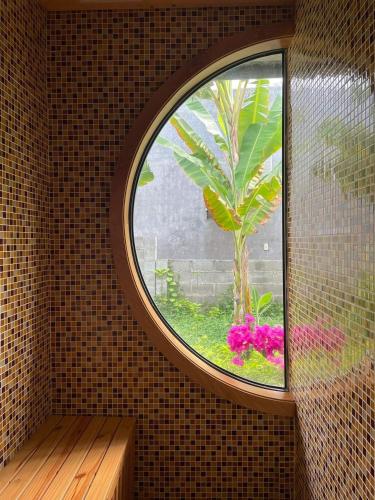 a round window in a room with a tree and pink flowers at GOLDEN LOTUS SPA & HOMESTAY in Ấp Thiện Phước