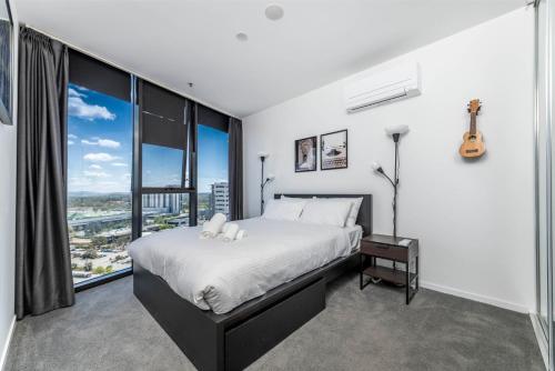 a bedroom with a bed and a large window at High Society Apartment Belconnen in Belconnen