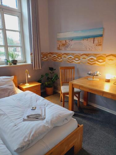 a bedroom with a bed and a desk and a table at Hotel Garni Kastanjehoff in Timmel