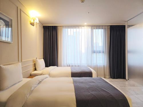 a hotel room with two beds and a window at JK Blossom Hotel in Seoul