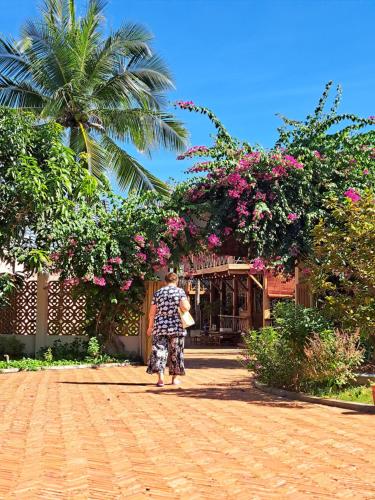 a woman standing in front of a building with flowers at GOLDEN LOTUS SPA & HOMESTAY in Ấp Thiện Phước