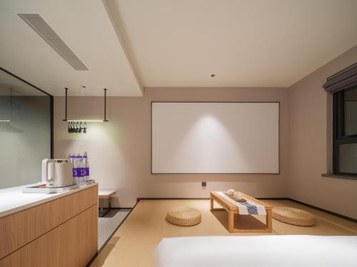 a room with a white projection screen and a table at 桔作酒店 郑州中州大道中原国际博览中心店 in Zhengzhou