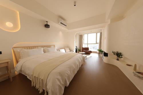 a white bedroom with a large bed and a window at Shanghai Suju Service Apartment Pudong Wanda Plaza Zhoupu Subway Station Branch in Shanghai