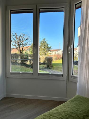 a room with three windows with a view of a tree at Dream-Stay I Zentral I cosy I Basel in Pratteln