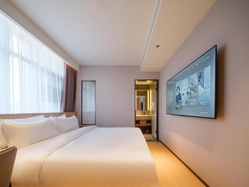 a hotel room with a bed and a flat screen tv at 桔作酒店 郑州中州大道中原国际博览中心店 in Zhengzhou