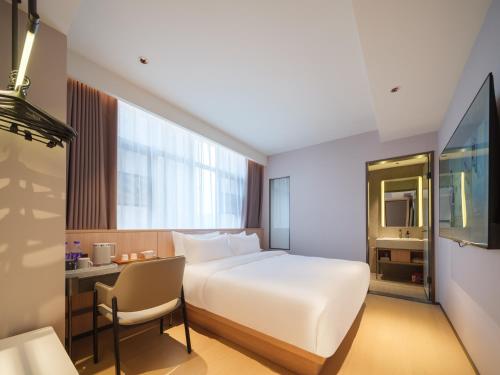 a hotel room with a bed and a desk and a chair at 桔作酒店 郑州中州大道中原国际博览中心店 in Zhengzhou