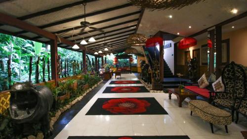 a lobby with red flowers on a tile floor at Jungle Retreat by Kupu Kupu Barong in Ubud