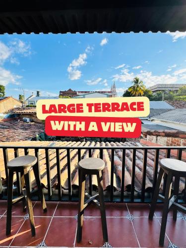 a large terrace with a view sign on a balcony with stools at Urban Nest Hostel in Santa Ana