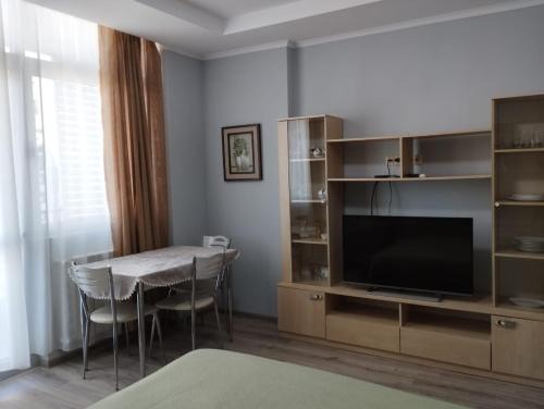 a living room with a table and a television at Yalcin Star Residence Apartment 300 in Batumi