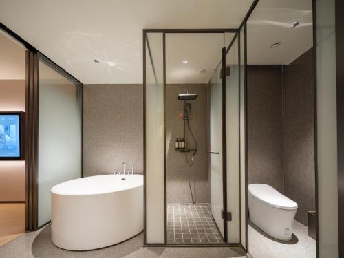 a bathroom with a tub and a sink and a toilet at 桔作酒店 郑州中州大道中原国际博览中心店 in Zhengzhou