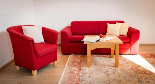 a living room with two red chairs and a coffee table at Hotel Garni Buchinger in St. Wolfgang