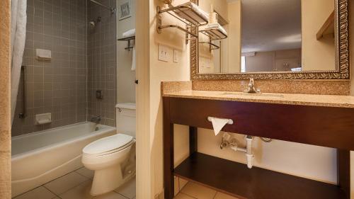 a bathroom with a toilet and a sink and a mirror at Baymont by Wyndham Rocky Mount I-95 in Rocky Mount