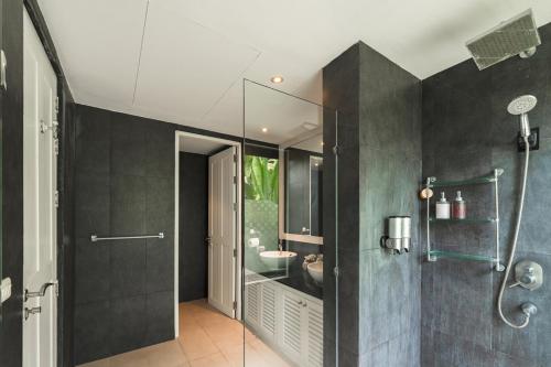 a bathroom with a glass shower and a sink at 芭东日月双海景别墅 in Patong Beach