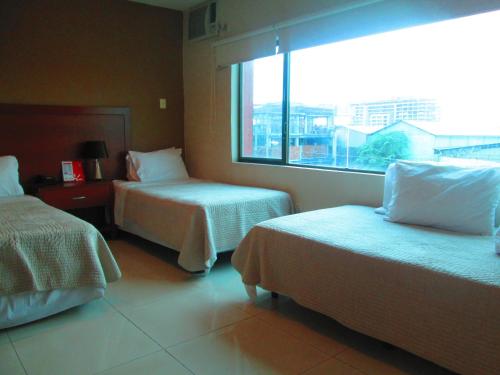 a hotel room with two beds and a window at Hotel Garzota Inn in Guayaquil