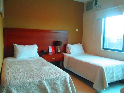 a hotel room with two beds and a window at Hotel Garzota Inn in Guayaquil
