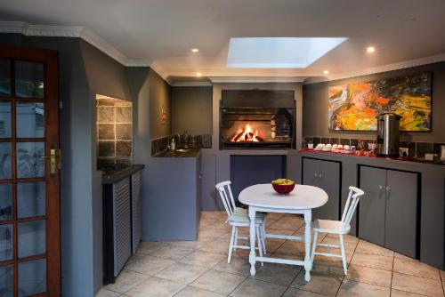 a kitchen with a table and a fire place at Sir Roys Guest House in Port Elizabeth
