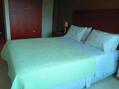 a bedroom with a large bed with white sheets and pillows at Hotel Garzota Inn in Guayaquil