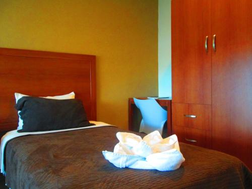a bedroom with a bed and a blue chair at Hotel Garzota Inn in Guayaquil