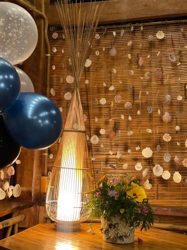 a lamp on a table with a vase of flowers and balloons at GOLDEN LOTUS SPA & HOMESTAY in Ấp Thiện Phước