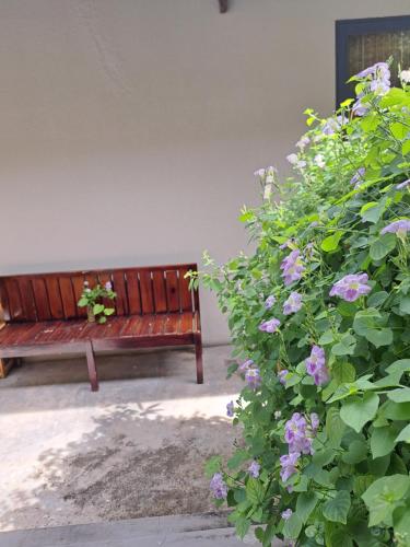 a wooden bench next to a bush with purple flowers at GOLDEN LOTUS SPA & HOMESTAY in Ấp Thiện Phước