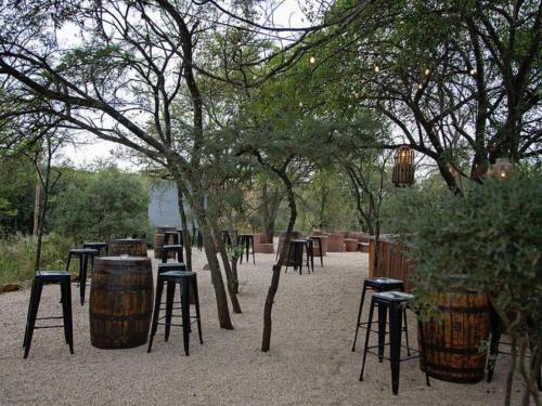 a group of bar stools and tables under some trees at Stay At Simbali in Tierpoort
