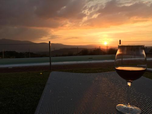 a glass of wine sitting on a table with the sunset at San Carlo a La Molinella in Città della Pieve