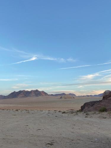 a view of the desert with mountains in the background at Wadi Rum Wild Camp Desert in Wadi Rum