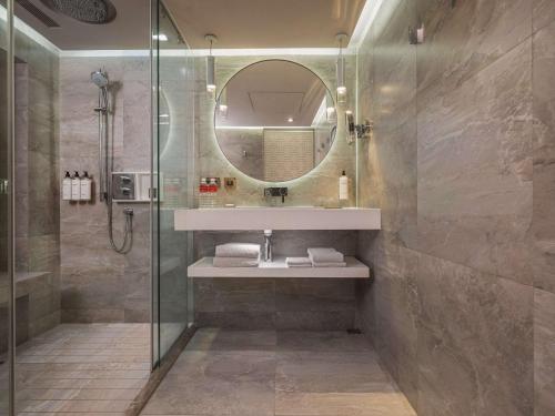 a bathroom with a shower and a sink and a mirror at Grand Hyatt Taipei in Taipei