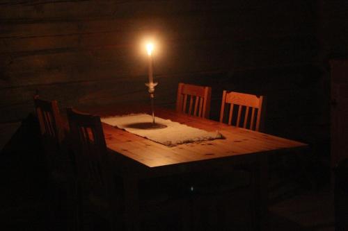 a candle sitting on top of a wooden table with chairs at Rustika strandstugor utanför Rättvik in Rättvik