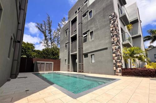 a swimming pool in front of a building at Coastal View 2 Apartments North in Grand Baie
