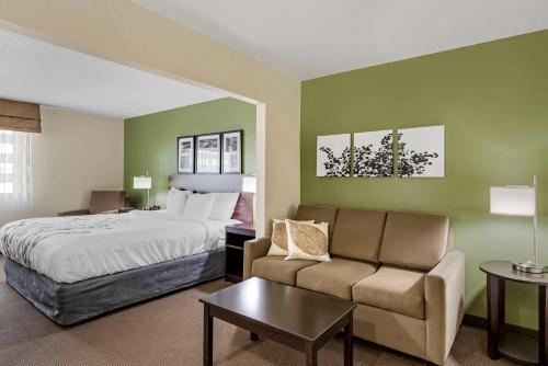a hotel room with a bed and a couch at Sleep Inn & Suites Charles City in Charles City