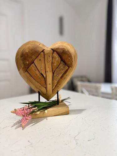 a wooden heart on a stand with flowers on a table at Forst-Ház Apartman in Eger