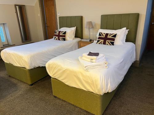 two beds in a hotel room with towels on them at Yorkshire Bridge Inn in Bamford