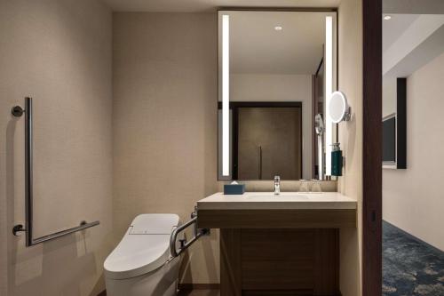 a bathroom with a toilet and a sink and a mirror at DoubleTree by Hilton Osaka Castle in Osaka