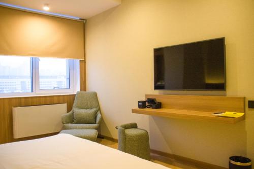 a hotel room with a bed and a tv and a chair at Resident Hotel Abay in Almaty