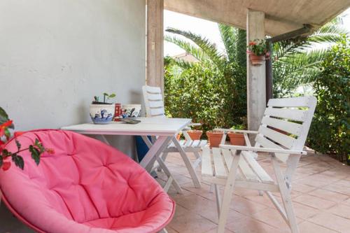 eine Terrasse mit einem Tisch, Stühlen und einem rosa Stuhl in der Unterkunft Apartment Camellie in Galižana